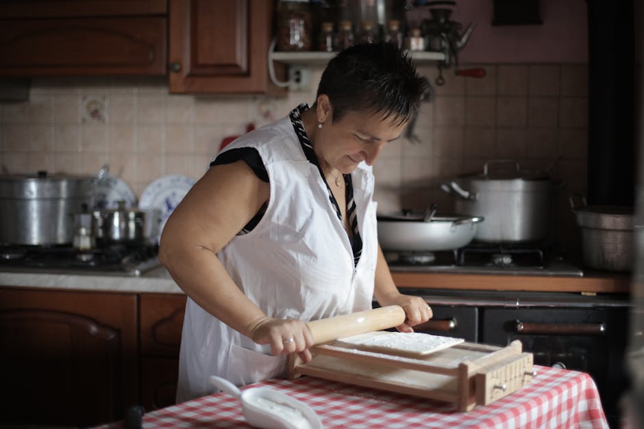 Elderly woman using rolling pin to prepare dough in a cozy kitchen.